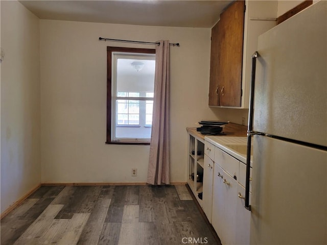 kitchen featuring white cabinets, refrigerator, and hardwood / wood-style flooring