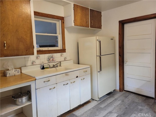 kitchen with decorative backsplash, white fridge, and light hardwood / wood-style flooring