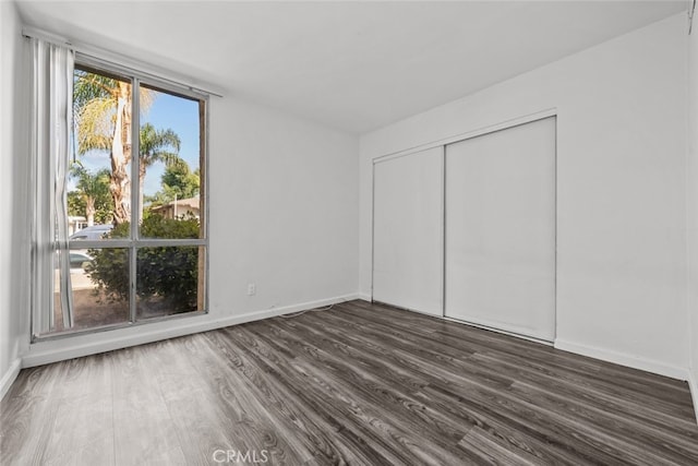 unfurnished bedroom with a closet and dark hardwood / wood-style flooring