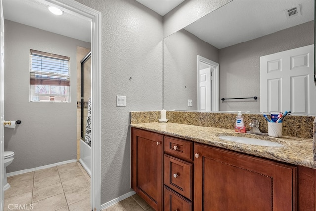 full bathroom featuring shower / bath combination with glass door, tile patterned flooring, vanity, and toilet