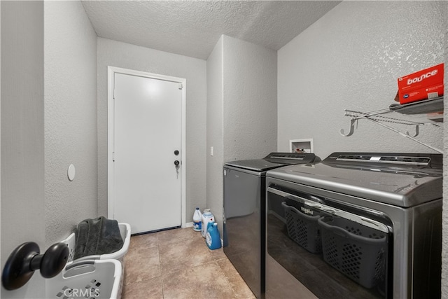 washroom with a textured ceiling and washing machine and dryer