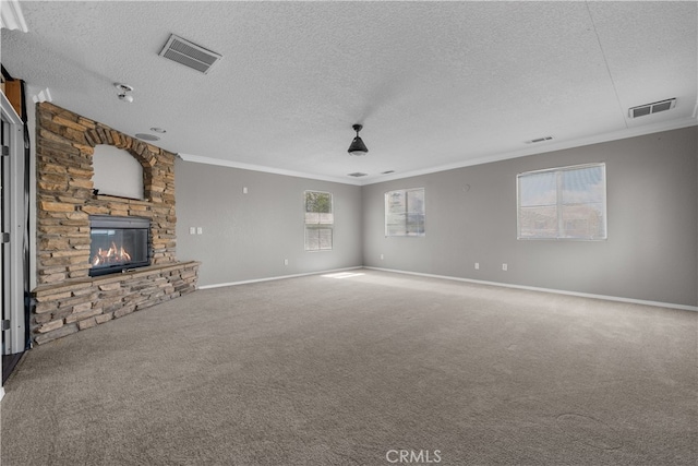 unfurnished living room featuring a stone fireplace, a textured ceiling, crown molding, and carpet flooring