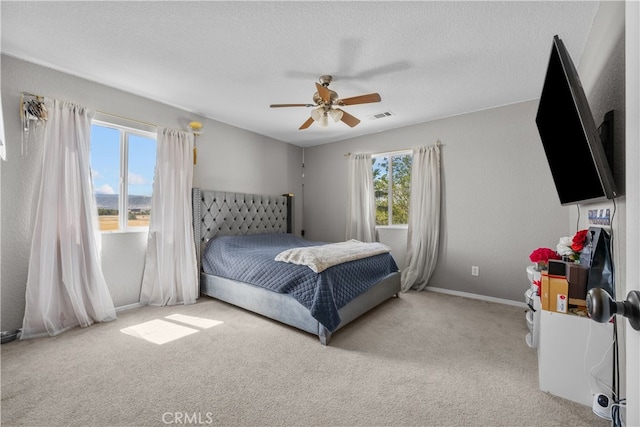 carpeted bedroom featuring multiple windows, a textured ceiling, and ceiling fan