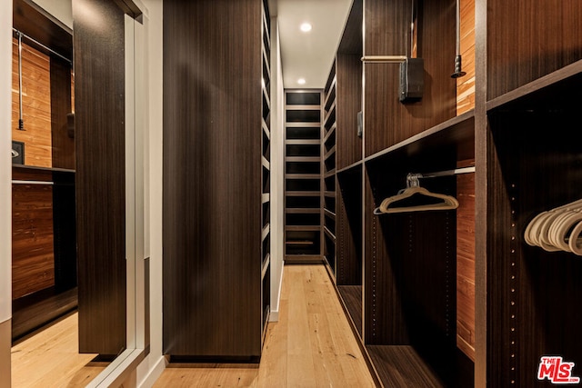 walk in closet with light hardwood / wood-style floors