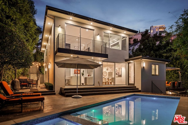 back of house with a pool side deck and a balcony