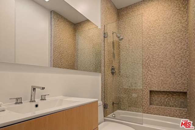 full bathroom featuring tiled shower / bath combo, vanity, and toilet