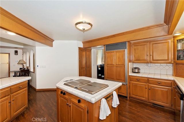 kitchen featuring tasteful backsplash, paneled built in refrigerator, dark hardwood / wood-style flooring, tile countertops, and a center island