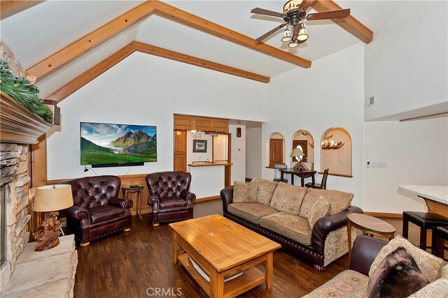 living room with ceiling fan, beam ceiling, dark wood-type flooring, high vaulted ceiling, and a fireplace