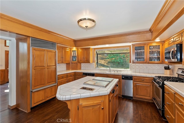 kitchen with paneled built in fridge, a center island, gas stove, tile counters, and dark hardwood / wood-style floors