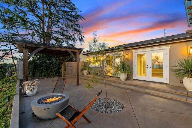 patio terrace at dusk featuring french doors, a fire pit, and a pergola