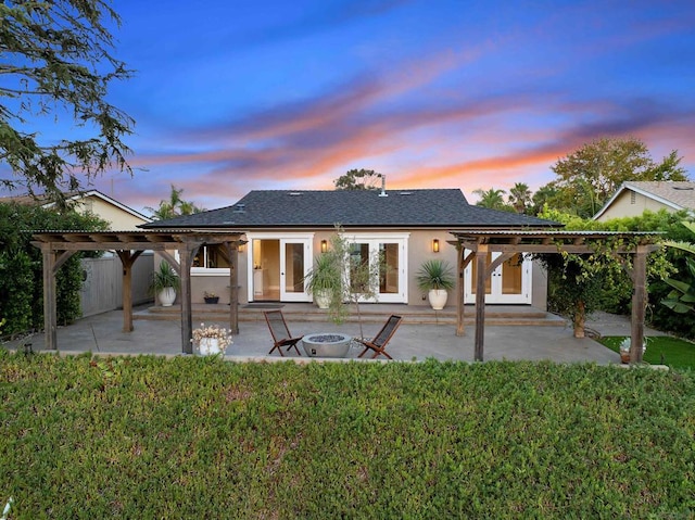 back house at dusk with a lawn, a pergola, and a patio area