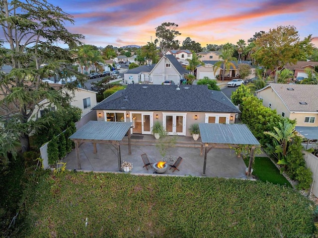 back house at dusk with french doors, a yard, and a patio area