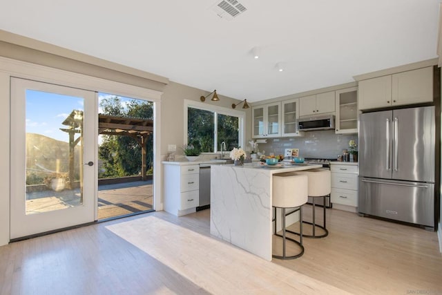 kitchen featuring appliances with stainless steel finishes, backsplash, light hardwood / wood-style floors, and a kitchen island