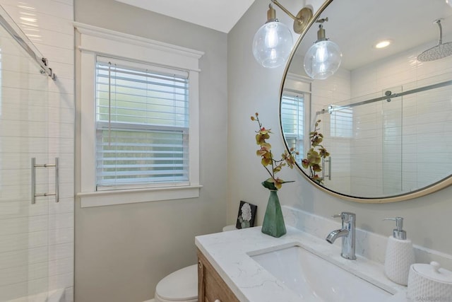 bathroom featuring vanity, toilet, and a shower with door