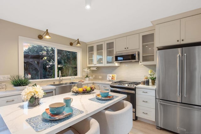 kitchen with light stone countertops, stainless steel appliances, a kitchen bar, and sink