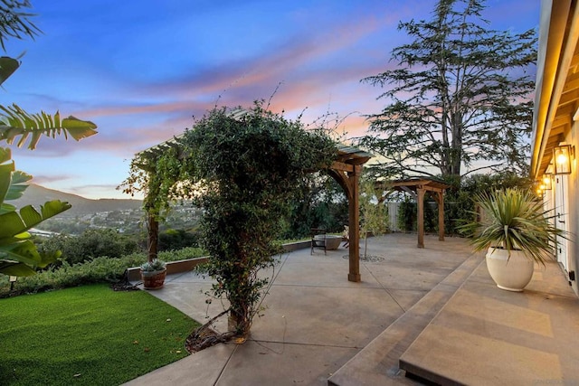 patio terrace at dusk featuring a yard and a mountain view