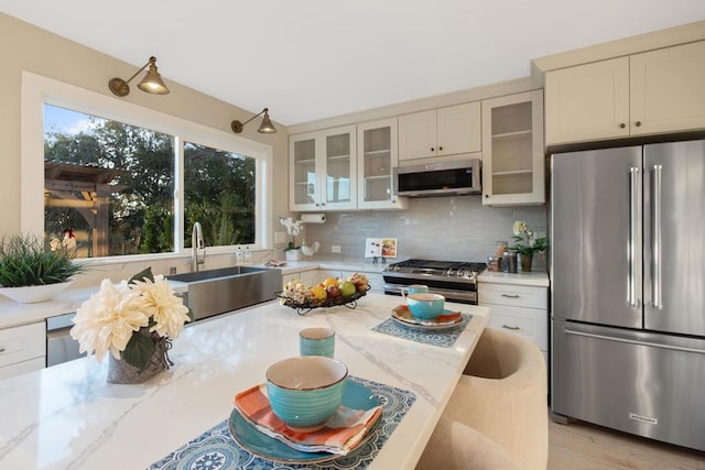 kitchen with light stone counters, appliances with stainless steel finishes, backsplash, and sink