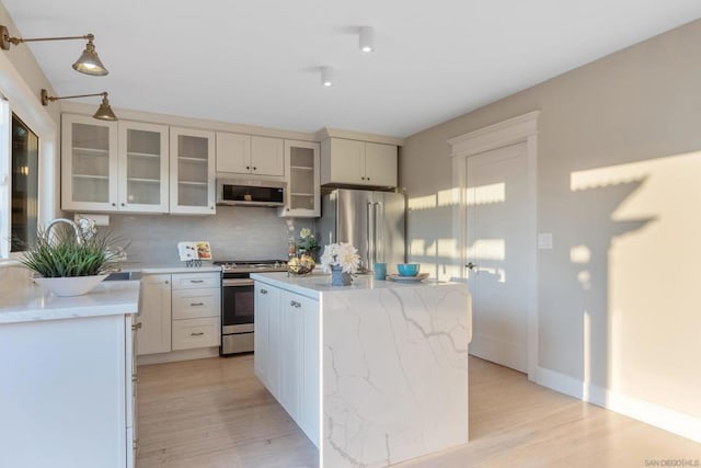 kitchen with appliances with stainless steel finishes, a kitchen island, and light hardwood / wood-style flooring