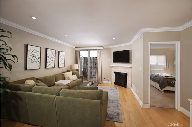 living room featuring ornamental molding, light hardwood / wood-style floors, and a tile fireplace