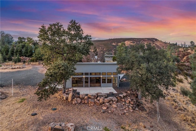 back house at dusk featuring a patio area and a mountain view