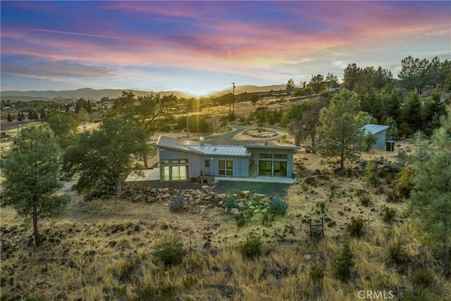 back house at dusk featuring a mountain view and a patio