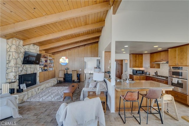 living room with sink, wood ceiling, a fireplace, and vaulted ceiling with beams