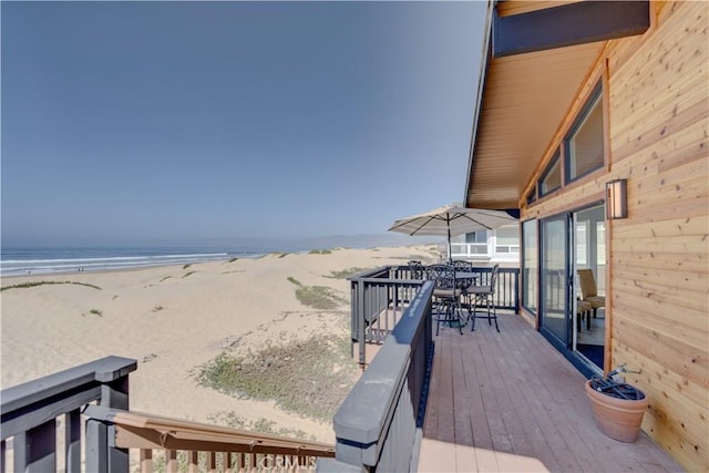 wooden deck with a water view and a beach view