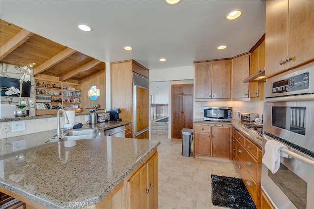 kitchen featuring appliances with stainless steel finishes, sink, decorative backsplash, light stone counters, and kitchen peninsula