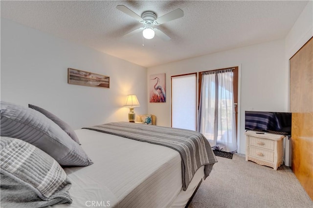 bedroom featuring light carpet, ceiling fan, and a textured ceiling