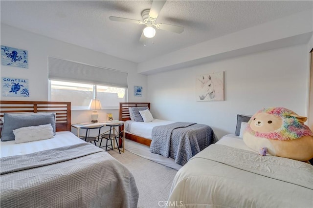 carpeted bedroom featuring ceiling fan and a textured ceiling