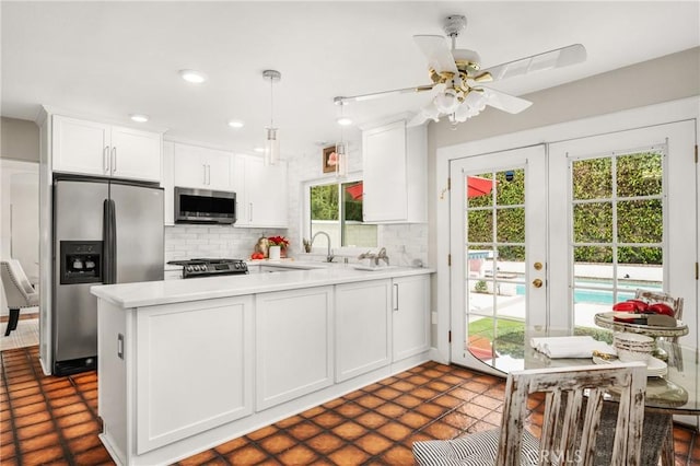 kitchen with ceiling fan, appliances with stainless steel finishes, white cabinets, and tasteful backsplash