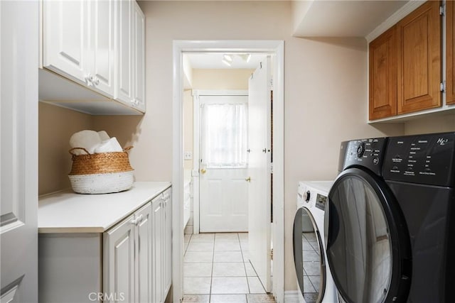 clothes washing area with cabinets, light tile patterned floors, and washing machine and dryer