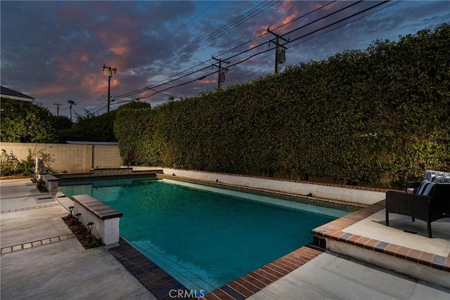 pool at dusk with a patio area