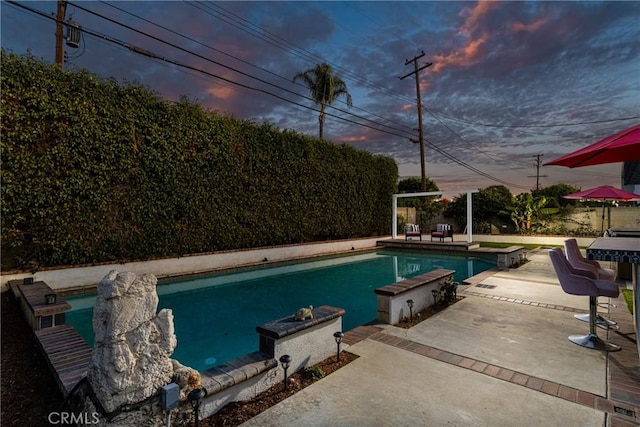 pool at dusk featuring a patio area