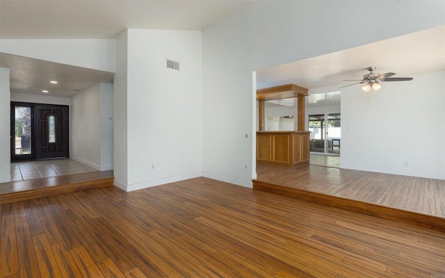 unfurnished living room with high vaulted ceiling, visible vents, baseboards, and wood finished floors