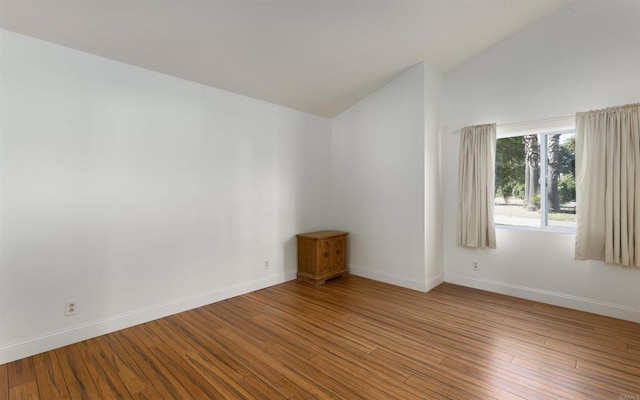 unfurnished room featuring lofted ceiling, wood finished floors, and baseboards