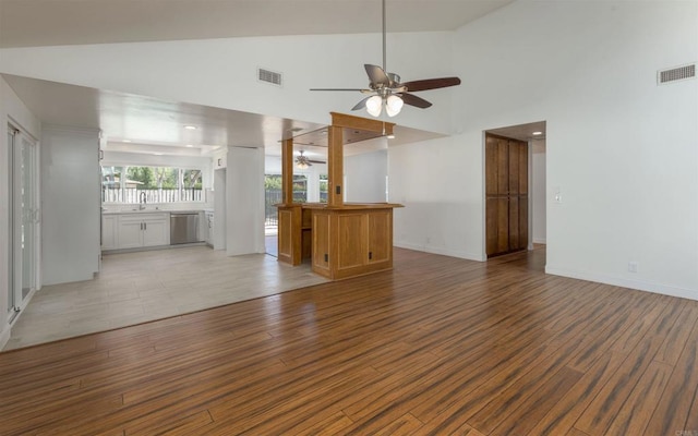 unfurnished living room with light wood-type flooring, high vaulted ceiling, visible vents, and a ceiling fan