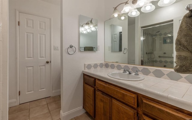 full bath featuring a stall shower, vanity, baseboards, and tile patterned floors