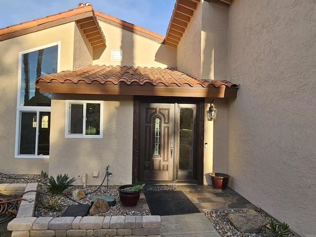 view of exterior entry featuring a tile roof and stucco siding