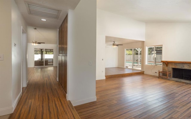 hallway with a wealth of natural light, visible vents, and dark wood-style flooring