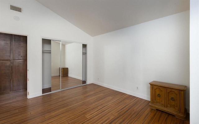 unfurnished bedroom with wood finished floors, visible vents, baseboards, vaulted ceiling, and a closet