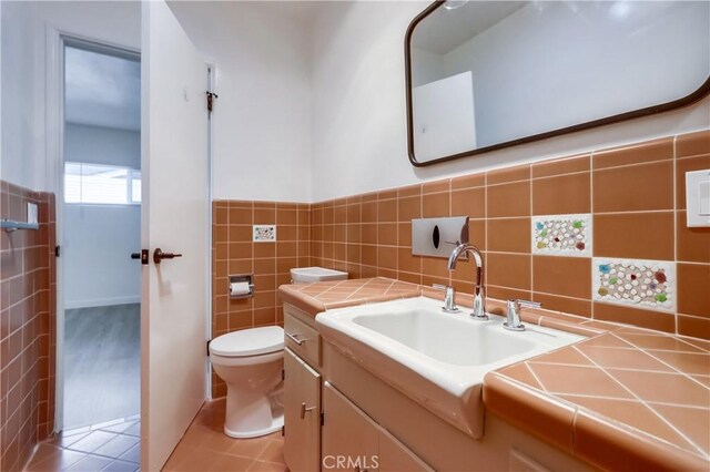 bathroom with tile walls, vanity, tile patterned flooring, and toilet