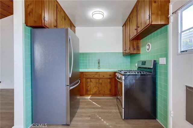 kitchen featuring appliances with stainless steel finishes, light hardwood / wood-style floors, sink, and backsplash