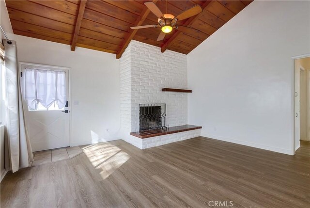 unfurnished living room with hardwood / wood-style flooring, wooden ceiling, a fireplace, and beamed ceiling