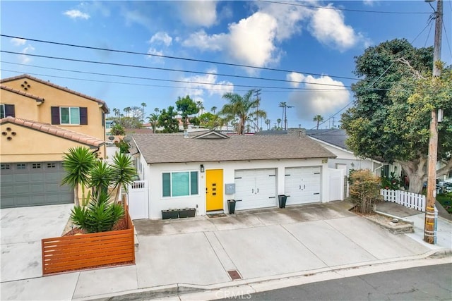 view of front facade featuring a garage, driveway, fence, and stucco siding