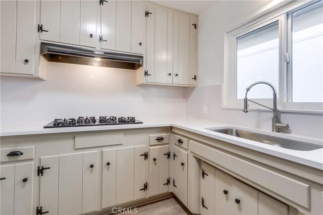 kitchen with sink, gas cooktop, and white cabinets