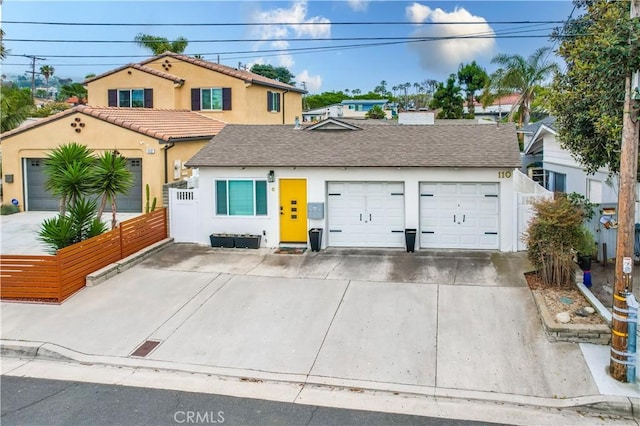 view of front of property featuring an attached garage, fence, concrete driveway, and stucco siding