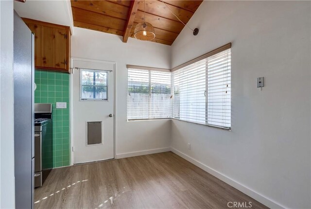 doorway with vaulted ceiling with beams, tile walls, wooden ceiling, and light wood-type flooring