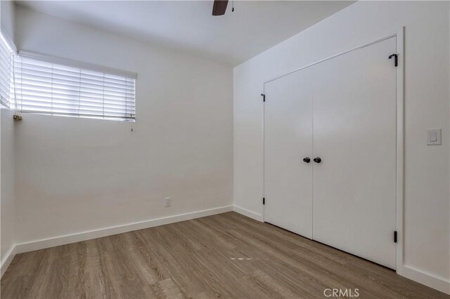 unfurnished bedroom with ceiling fan, light wood-type flooring, and a closet