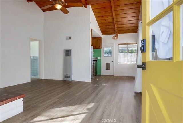 unfurnished living room featuring high vaulted ceiling, wooden ceiling, hardwood / wood-style flooring, ceiling fan, and beam ceiling